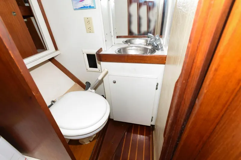 Slide: The Image of 1977 Gulfstar 50 Center Cockpit bathroom with sink, mirror, and toilet. - 28