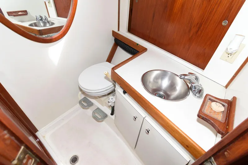 Slide: The Image of 1977 Gulfstar 50 Center Cockpit bathroom with sink, toilet, and wooden accents. - 30
