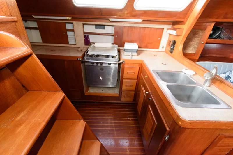 Slide: The Image of 1977 Gulfstar 50 Center Cockpit galley with wooden cabinetry and stainless steel appliances. - 31