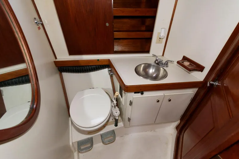 Slide: The Image of 1977 Gulfstar 50 Center Cockpit bathroom with sink, toilet, and wooden cabinets. - 37