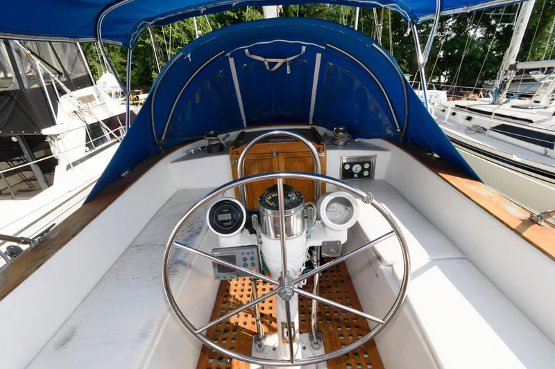 Slide: The Image of 1977 Gulfstar 50 Center Cockpit sailboat helm with blue canopy and wooden accents. - 9