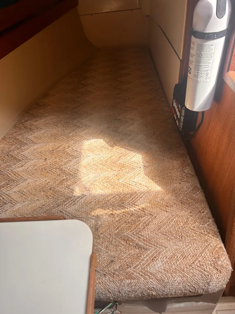 Slide: The Image of Interior cabin of a 1983 O'Day 30 sailboat with cushioned seating and fire extinguisher. - 10