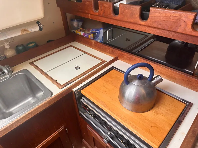 Slide: The Image of Compact kitchen area in a 1983 O'Day 30 sailboat with a kettle on the stove. - 13