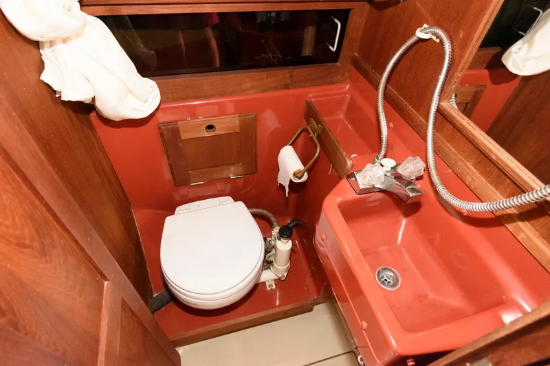 Slide: The Image of 1983 O'Day 30 sailboat bathroom with toilet, sink, and wooden cabinetry. - 16