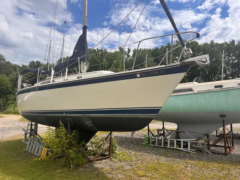 Slide: The Image of 1983 O'Day 30 sailboat on stands in a boatyard under a partly cloudy sky. - 3