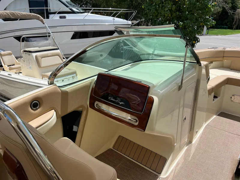 Slide: The Image of 2024 Chris-Craft Launch 25 GT boat interior with beige seating and wooden dashboard. - 11