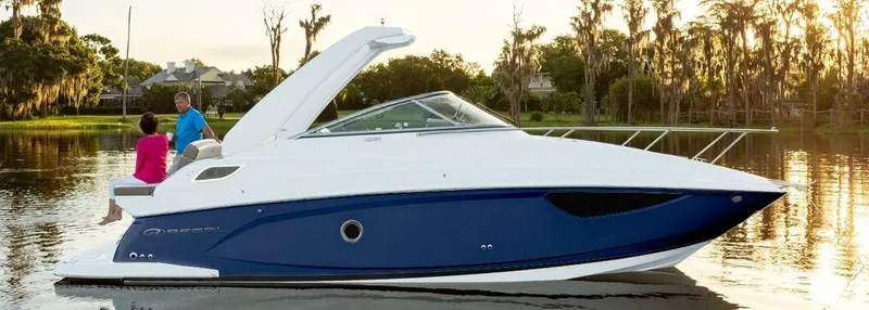 Slide: The Image of 2025 Regal 28X boat on a serene lake with two people onboard. - 0