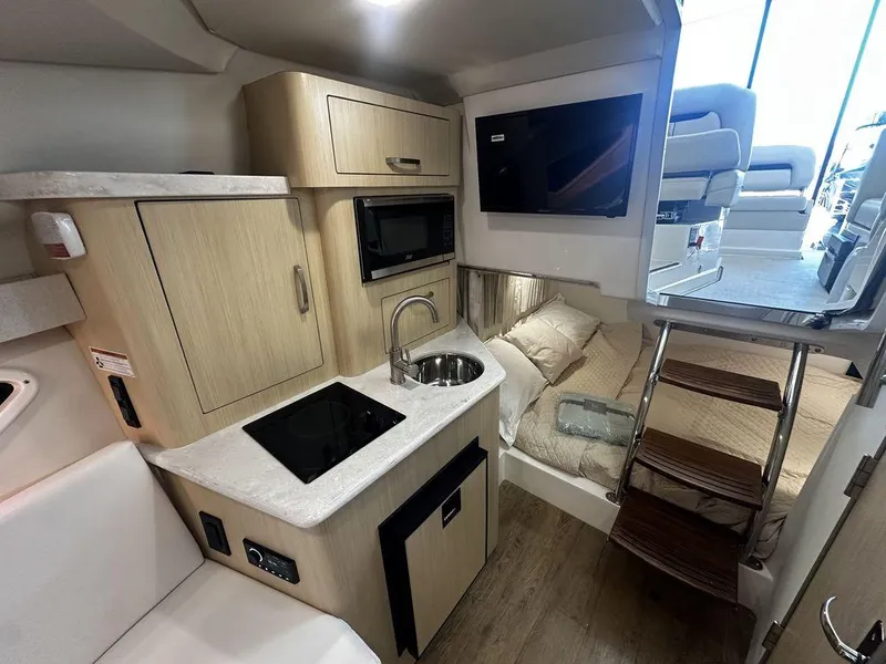 Slide: The Image of 2025 Regal 28X boat interior with kitchenette, bed, and stairs. - 4
