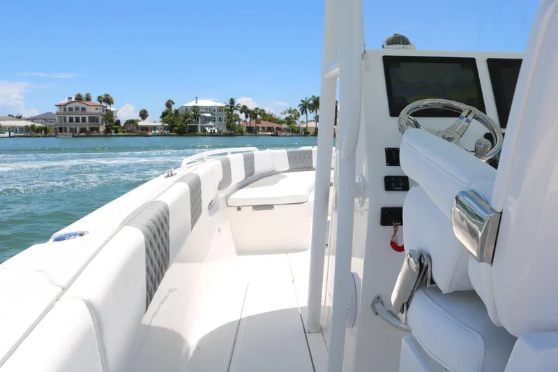 Slide: The Image of 2016 Stamas 317 Tarpon boat interior with white seating and steering console on the water. - 23