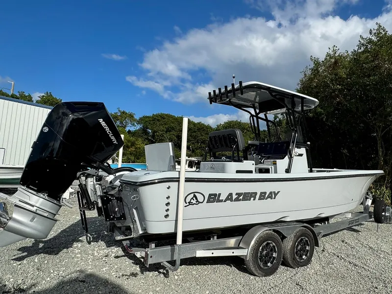Slide: The Image of 2025 Blazer 2700 HYBRID BAY boat on trailer, featuring Mercury outboard motor. - 2