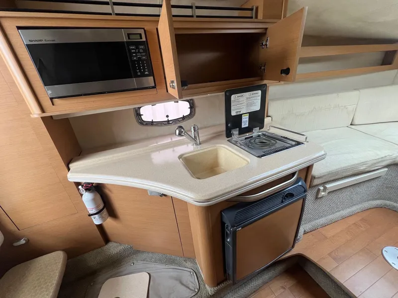 Slide: The Image of 2009 Sea Ray 270 Sundancer interior kitchen with microwave, sink, and stove. - 10