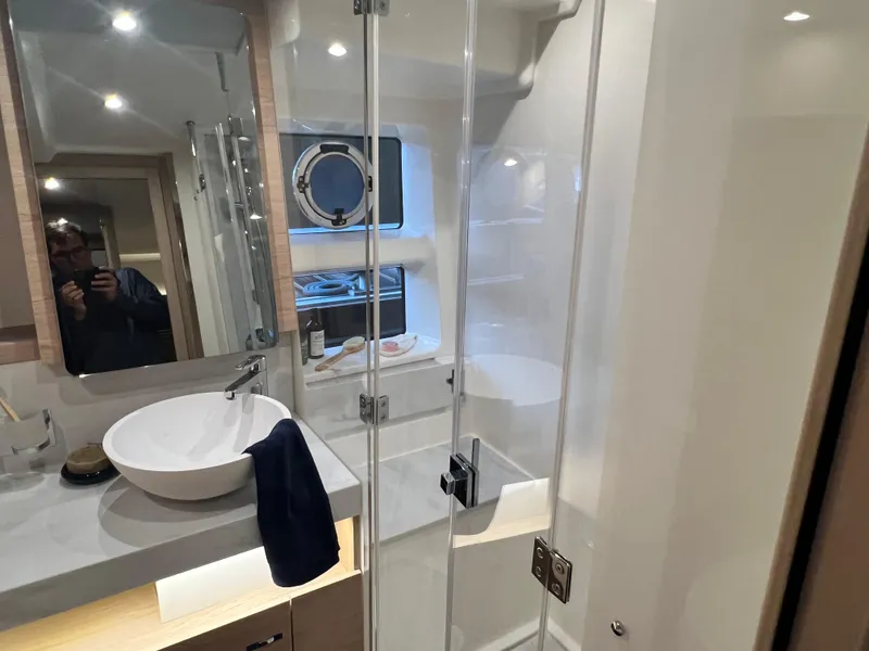 Slide: The Image of Modern bathroom on 2025 Beneteau Swift Trawler 54 with glass shower and vessel sink. - 18