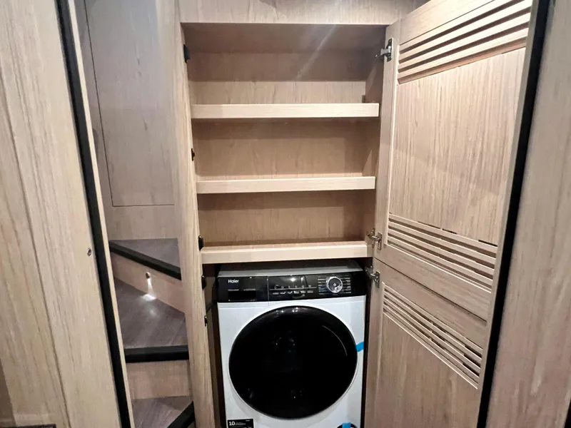 Slide: The Image of Laundry area with washer and storage shelves in 2025 Beneteau Swift Trawler 54. - 19
