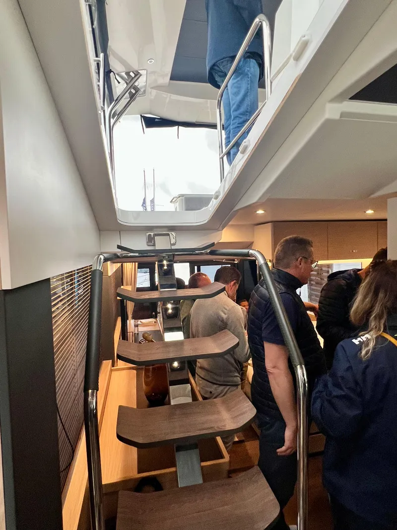 Slide: The Image of Interior of 2025 Beneteau Swift Trawler 54 with staircase and people. - 21