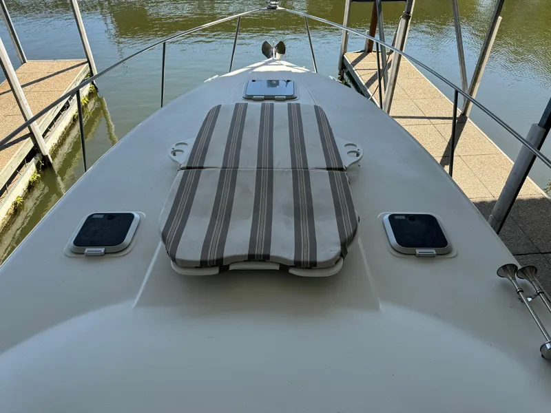 Slide: The Image of 2008 Rinker 370 boat deck with striped sun pad, docked by the water. - 17