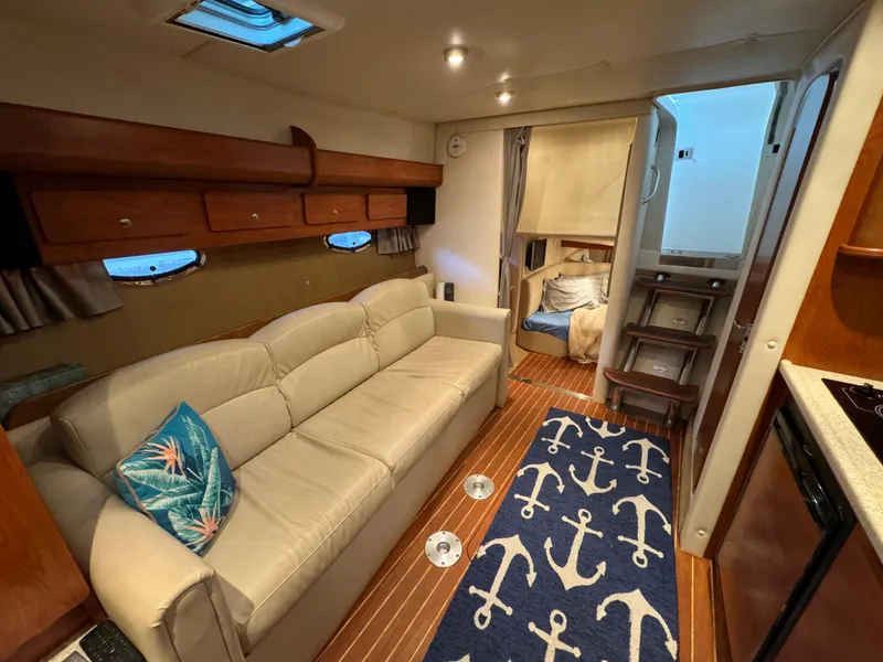 Slide: The Image of 2008 Rinker 370 yacht interior with beige sofa, nautical decor, and cozy cabin space. - 19