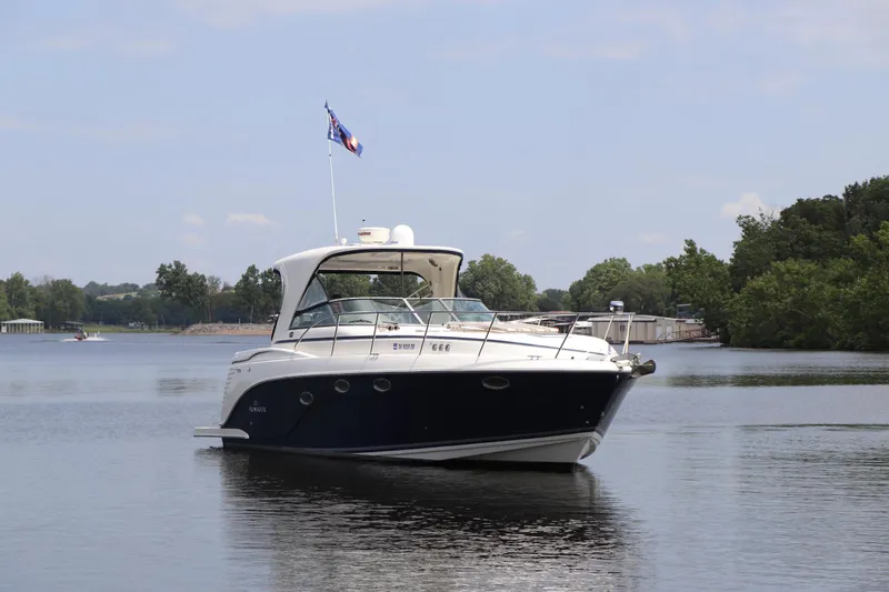 Slide: The Image of 2008 Rinker 370 boat cruising on a calm lake with trees in the background. - 3