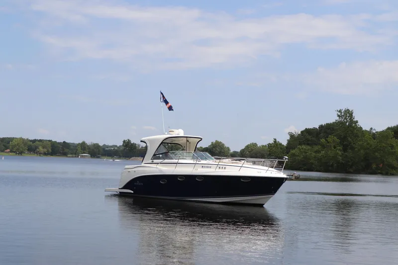 Slide: The Image of 2008 Rinker 370 boat cruising on a calm lake with trees in the background. - 4