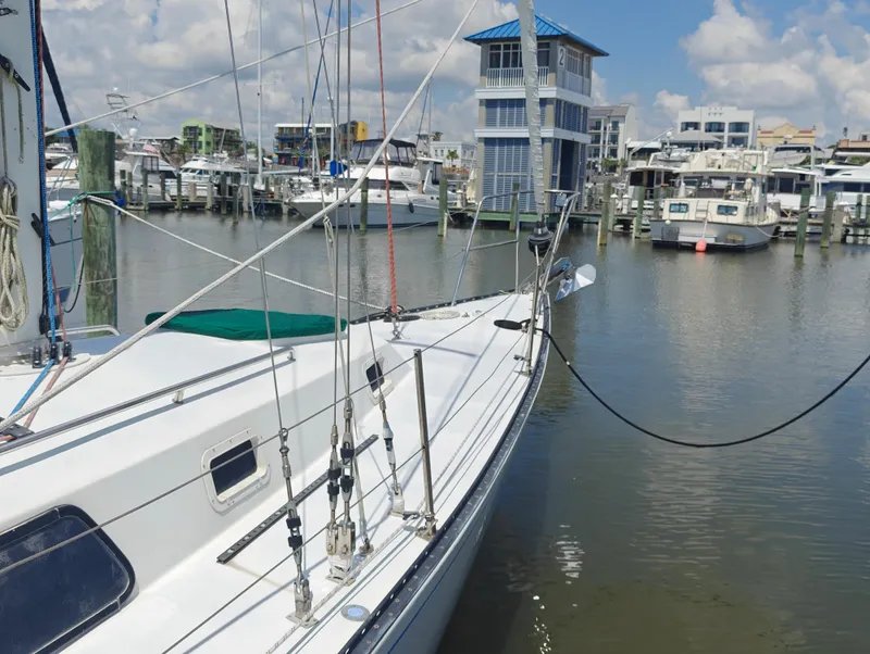 Slide: The Image of Sailboat Newport MKII 1987 docked in a marina with other boats and buildings. - 4