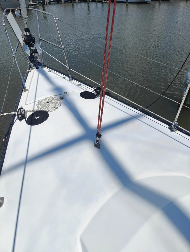 Slide: The Image of Bow of 1987 Newport MKII sailboat with ropes and railing, docked on calm water. - 8