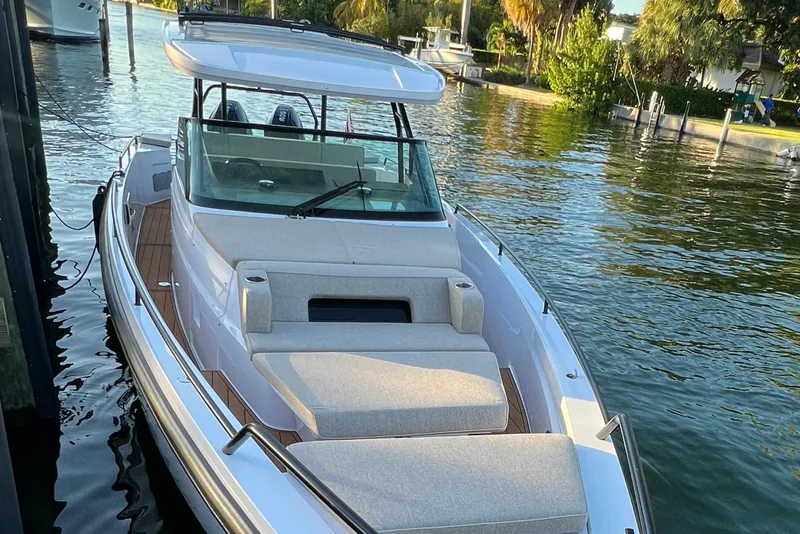 Slide: The Image of 2023 Axopar 37 Sun-Top boat docked in a serene waterfront setting. - 10