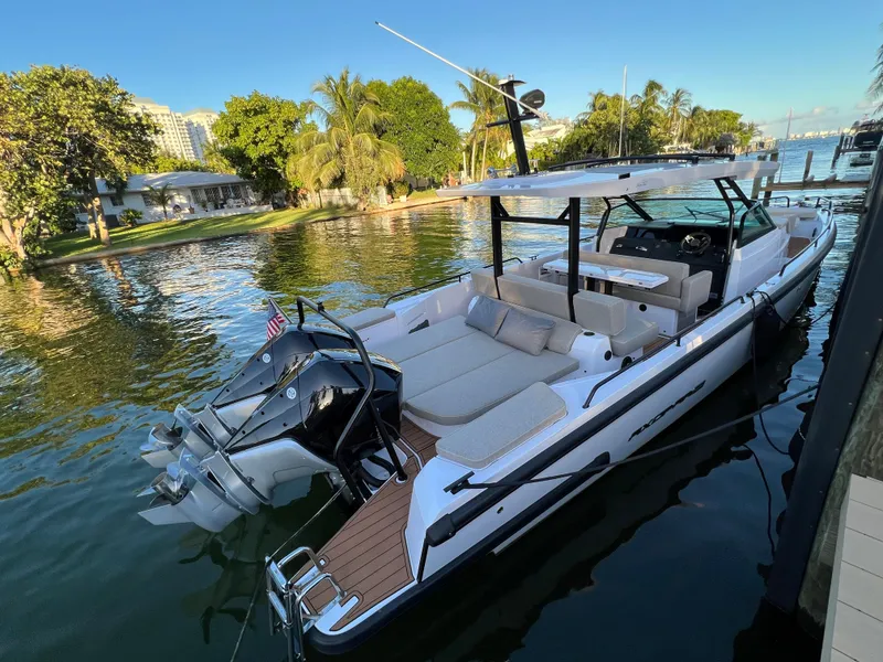 Slide: The Image of 2023 Axopar 37 Sun-Top luxury motorboat docked by a scenic waterfront. - 11