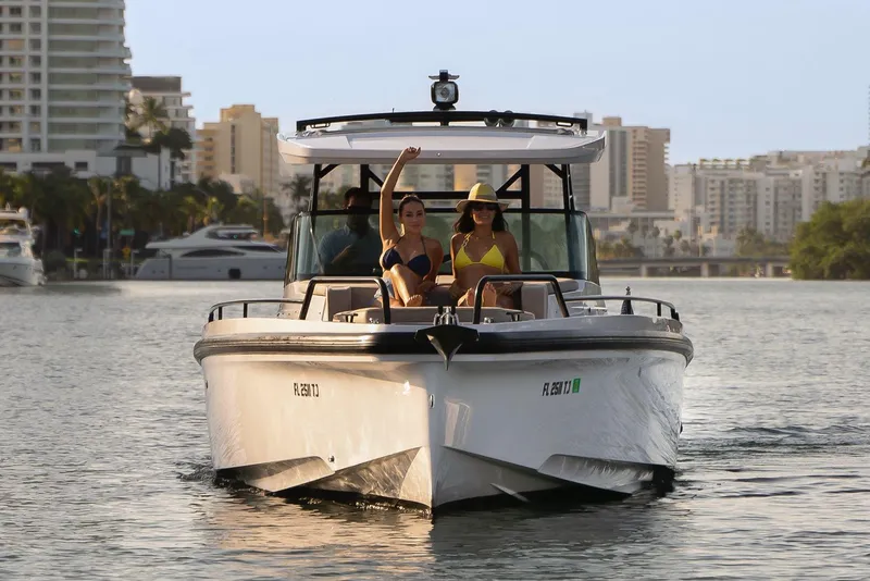 Slide: The Image of 2023 Axopar 37 Sun-Top boat cruising with passengers in a city waterfront. - 2