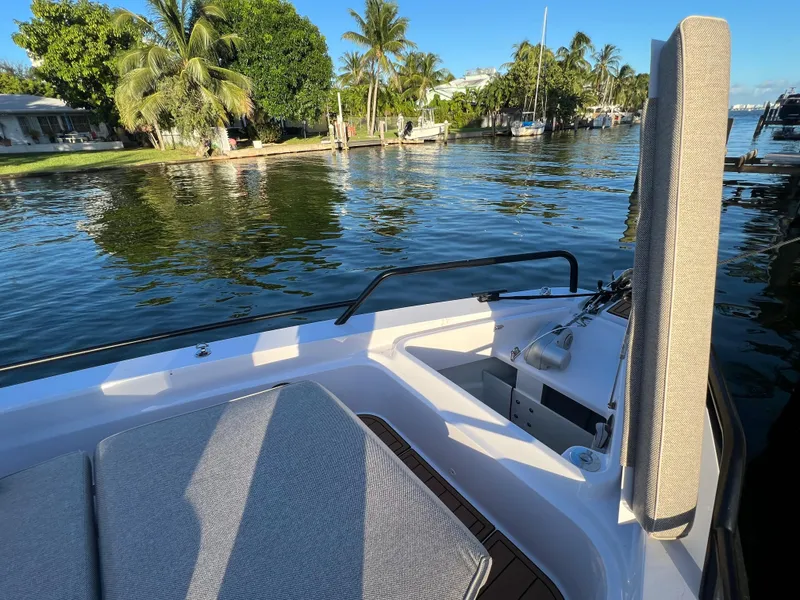 Slide: The Image of 2023 Axopar 37 Sun-Top boat on a serene waterfront with lush palm trees. - 35