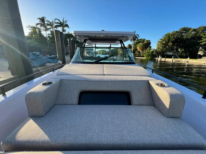 Slide: The Image of 2023 Axopar 37 Sun-Top boat with cushioned seating, docked by a serene waterfront. - 41