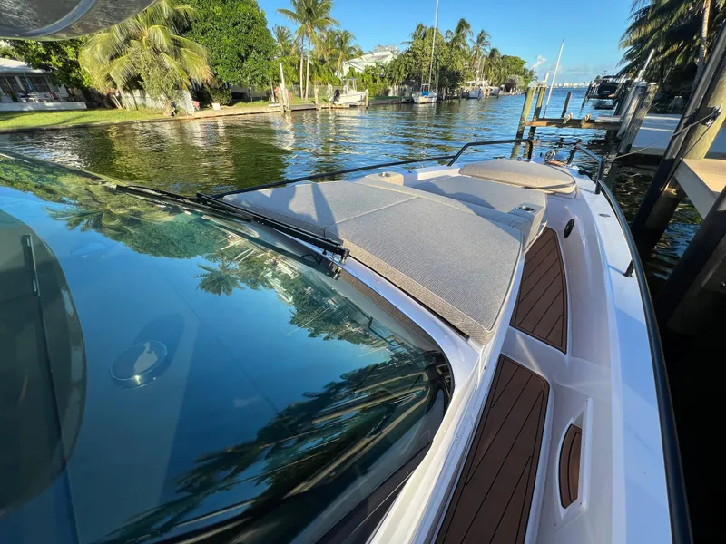 Slide: The Image of 2023 Axopar 37 Sun-Top boat docked by a scenic waterfront with lush greenery. - 48