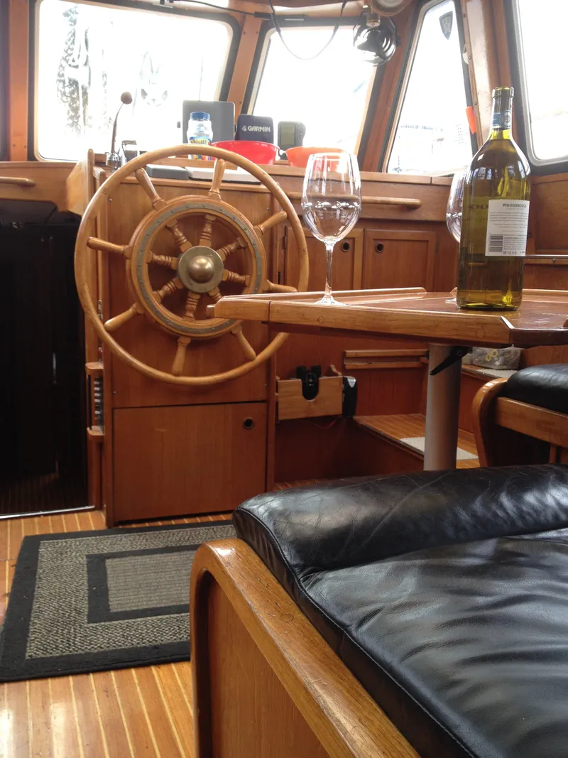 Slide: The Image of Interior of 1985 Nauticat 38 sailboat with wooden helm, table, and wine bottle. - 32