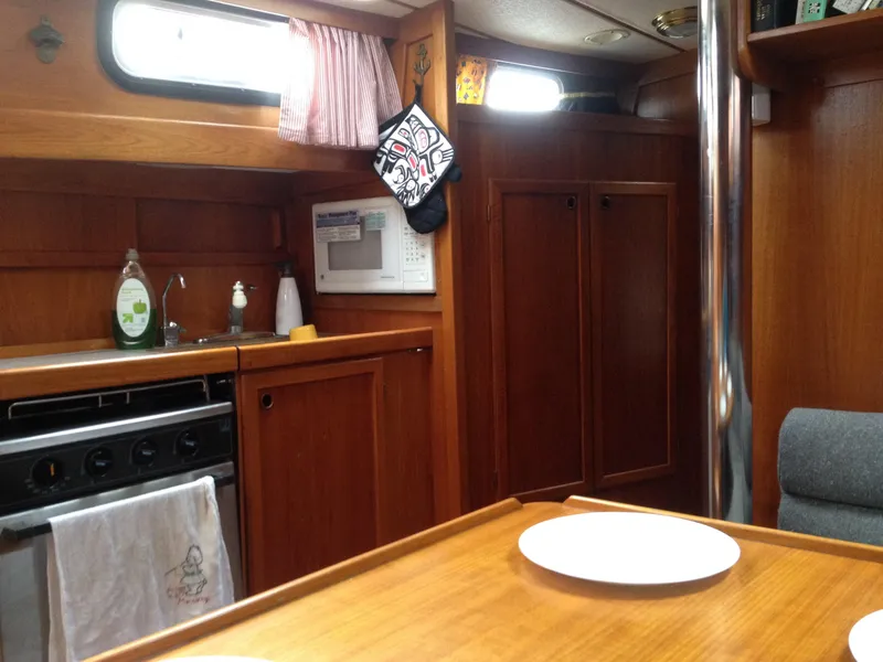 Slide: The Image of Interior of 1985 Nauticat 38 sailboat kitchen with wooden cabinetry and dining area. - 40
