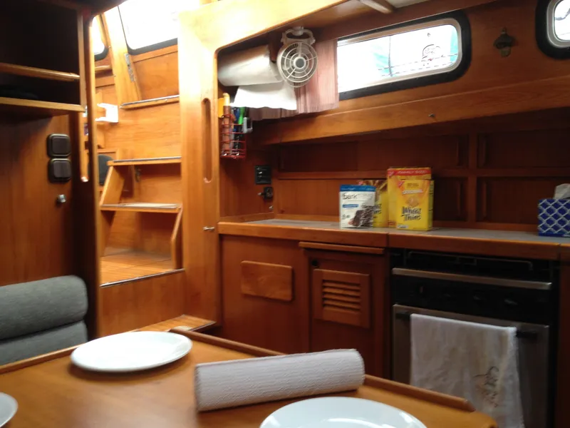 Slide: The Image of 1985 Nauticat 38 interior kitchen with wooden cabinetry and dining area. - 43