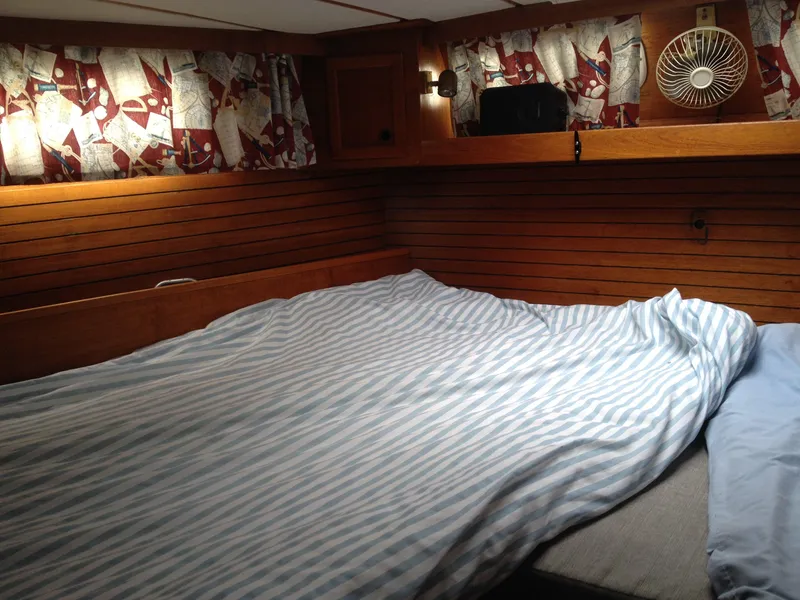 Slide: The Image of Cozy cabin bedroom in a 1985 Nauticat 38 sailboat with striped bedding. - 48