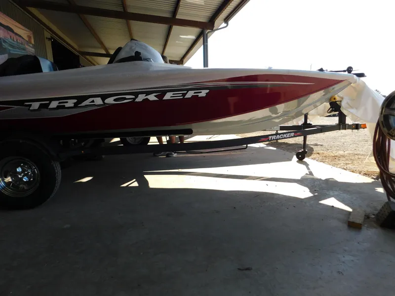 Slide: The Image of 2024 Tracker Pro 170 boat in a shaded area, partially covered, on a trailer. - 27