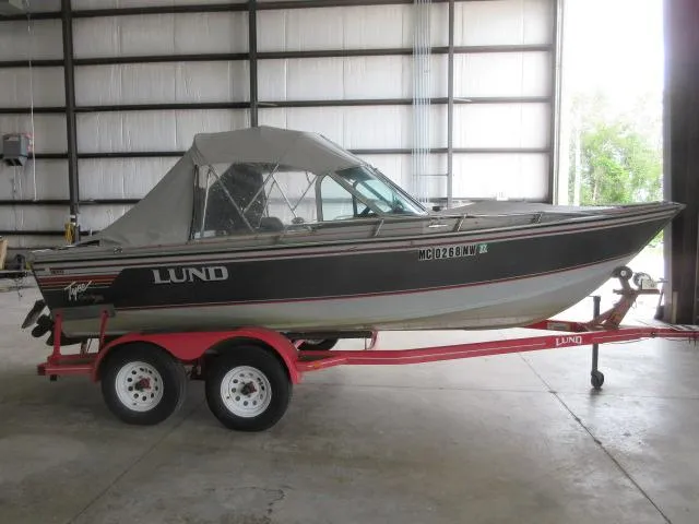 Slide: The Image of 1990 Lund 1850 Tyee Gran Sport boat on a red trailer in a warehouse. - 4