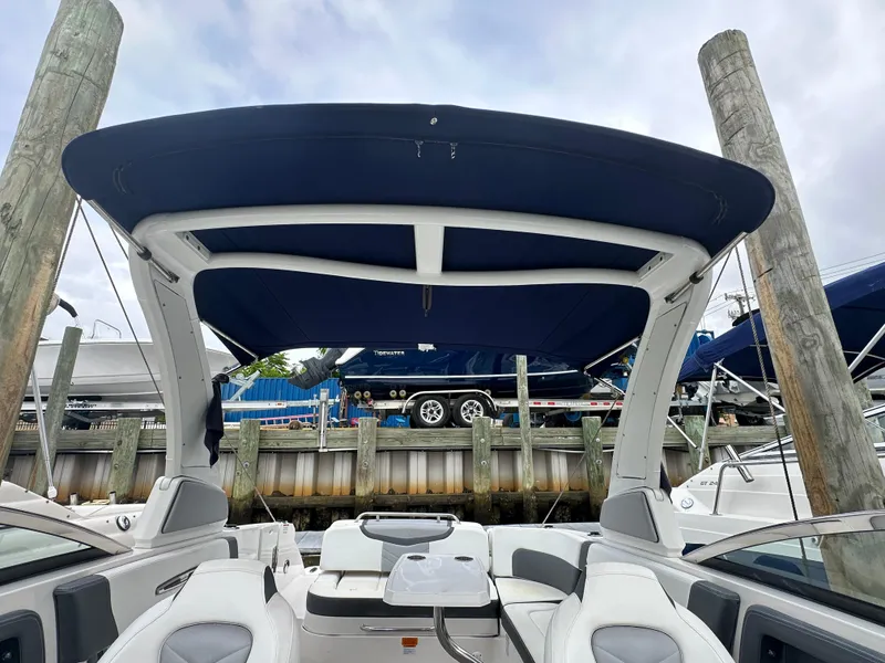 Slide: The Image of 2018 Chaparral 267 SSX boat with blue bimini top docked at marina. - 14