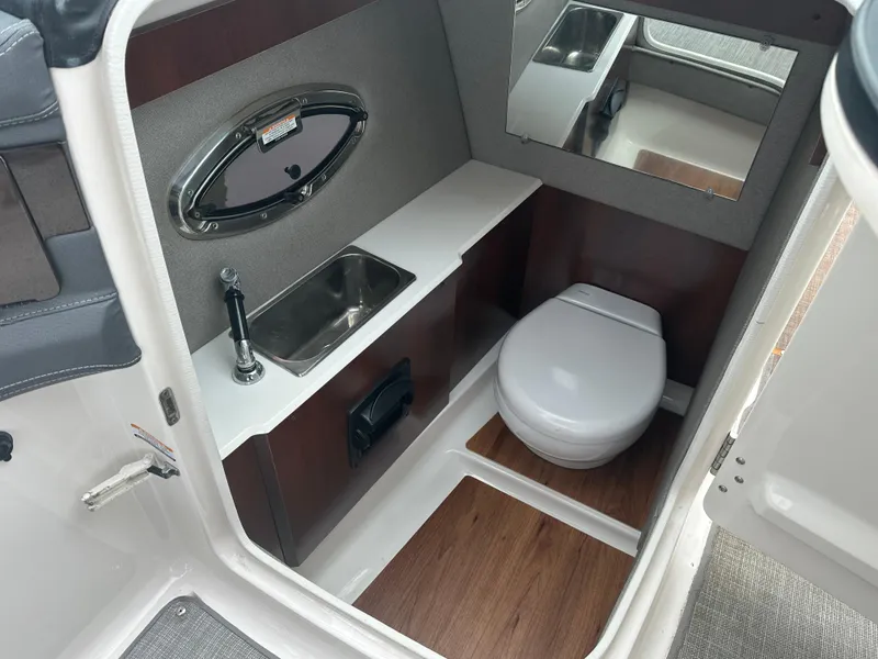 Slide: The Image of 2018 Chaparral 267 SSX boat interior bathroom with sink, toilet, and mirror. - 8