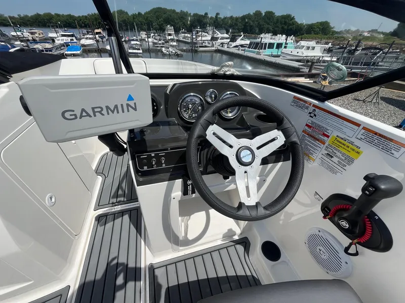 Slide: The Image of 2022 Bayliner VR4 Bowrider OB cockpit with Garmin navigation, steering wheel, and marina view. - 6