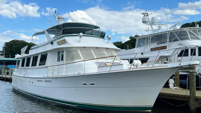 The Image of 1987 Hatteras Motoryacht docked, featuring classic design and spacious deck under a blue sky. - 0