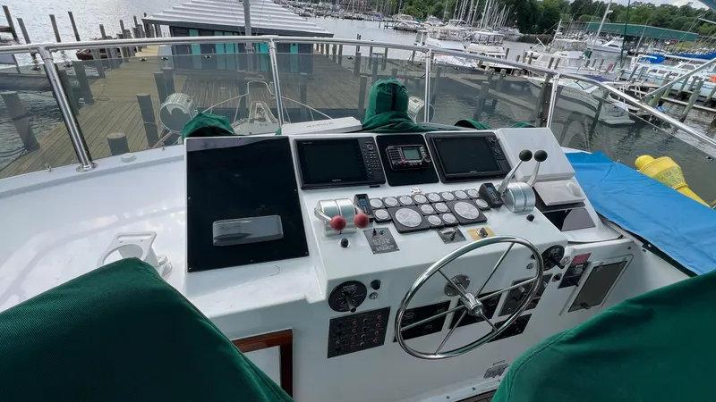 Slide: The Image of 1987 Hatteras Motoryacht helm with navigation instruments, docked at a marina. - 14