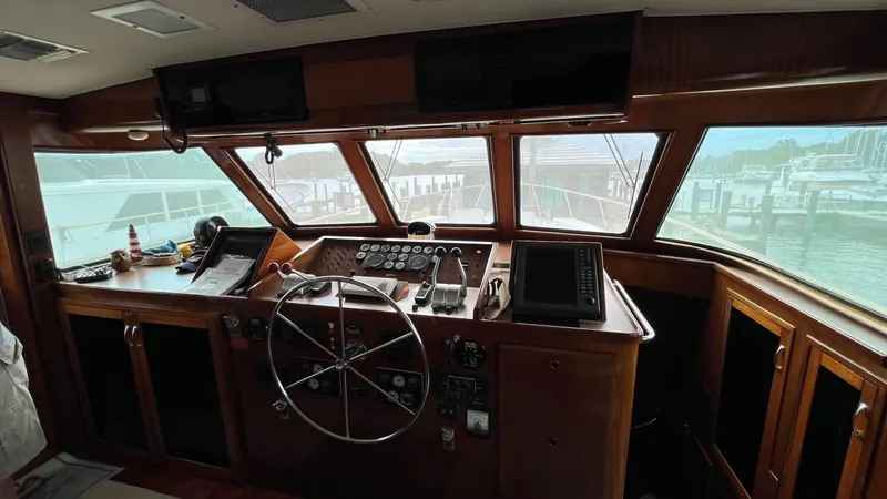 Slide: The Image of 1987 Hatteras Motoryacht helm with wooden dashboard and steering wheel, marina view through windows. - 16