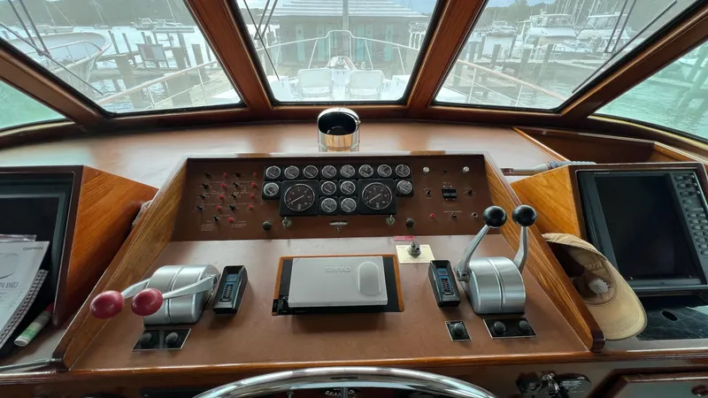 Slide: The Image of 1987 Hatteras Motoryacht helm with classic controls and gauges, overlooking marina. - 18