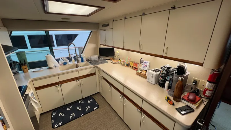 Slide: The Image of 1987 Hatteras Motoryacht kitchen with white cabinets, appliances, and nautical-themed decor. - 2