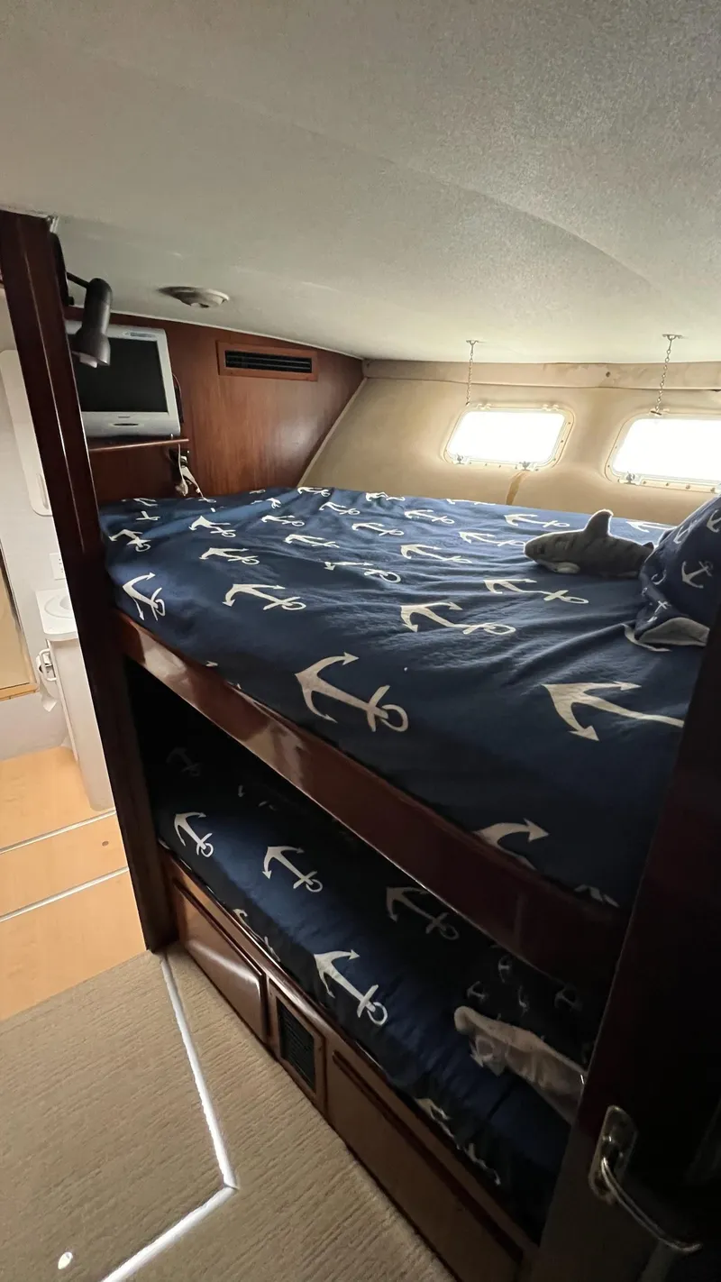 Slide: The Image of 1987 Hatteras Motoryacht cabin with anchor-themed bedding and natural light. - 21