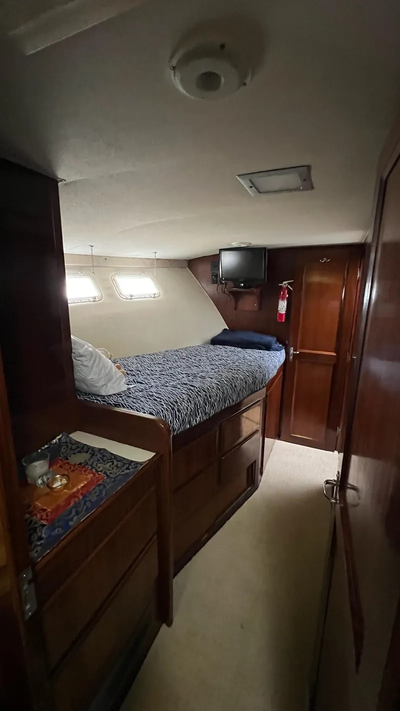 Slide: The Image of 1987 Hatteras Motoryacht cabin interior with bed, wooden cabinets, and small TV. - 25
