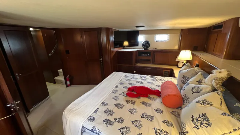 Slide: The Image of Luxurious bedroom interior of a 1987 Hatteras Motoryacht with elegant bedding and wooden furnishings. - 32
