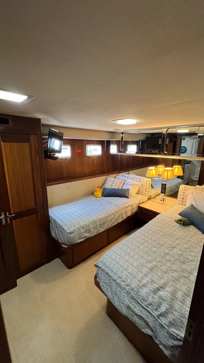 Slide: The Image of 1987 Hatteras Motoryacht cabin with twin beds, wood paneling, and cozy lighting. - 38