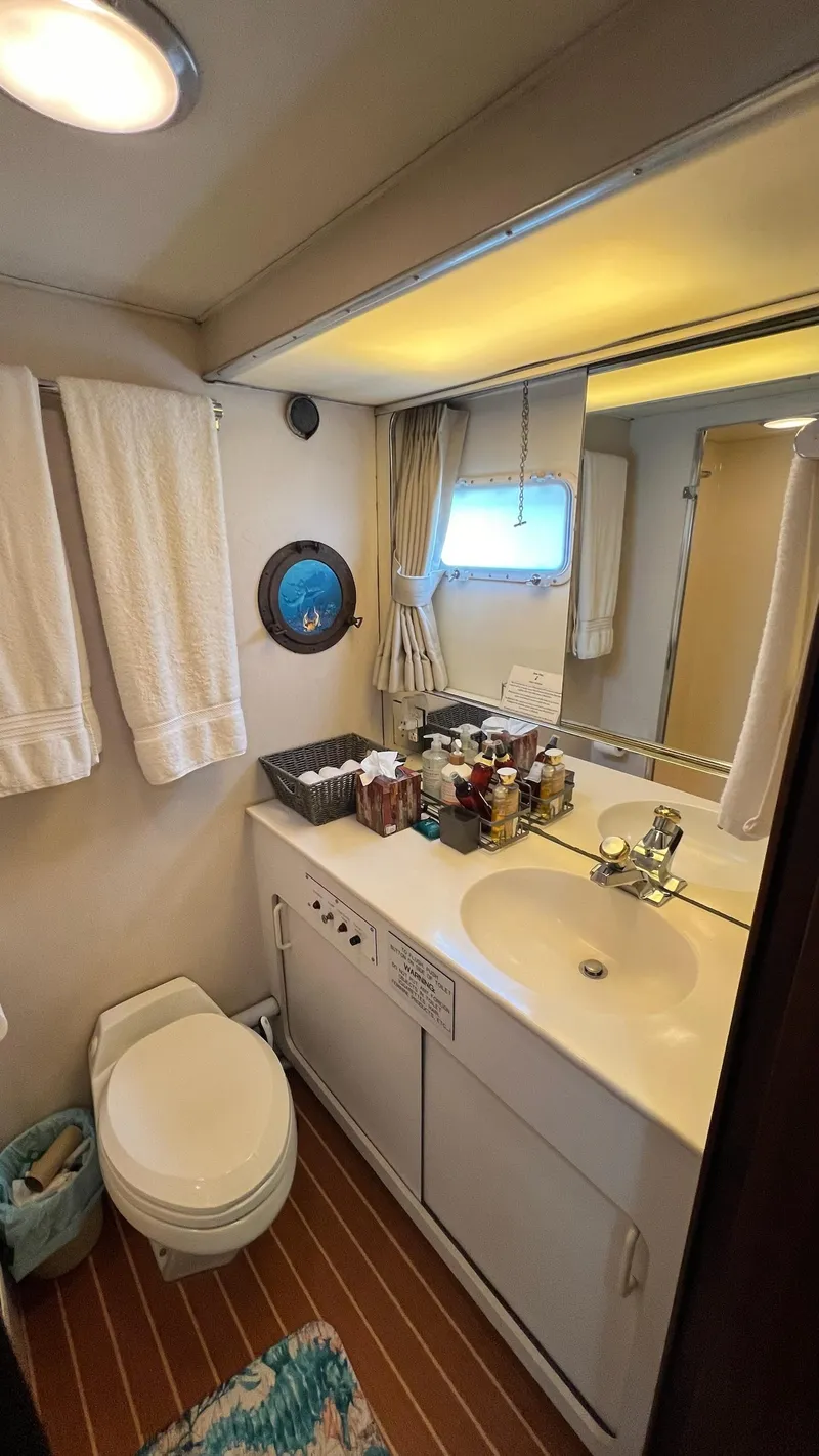 Slide: The Image of 1987 Hatteras Motoryacht bathroom with sink, mirror, and toilet, featuring nautical decor. - 39