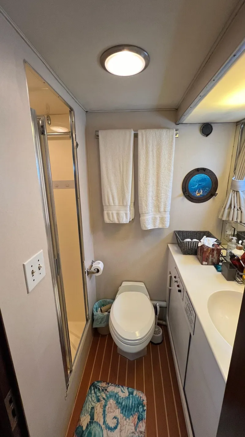 Slide: The Image of 1987 Hatteras Motoryacht bathroom with shower, toilet, vanity, and nautical decor. - 40